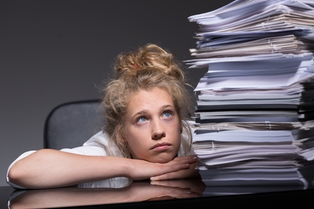 Portrait of depressed girl overhelmed by paperwork